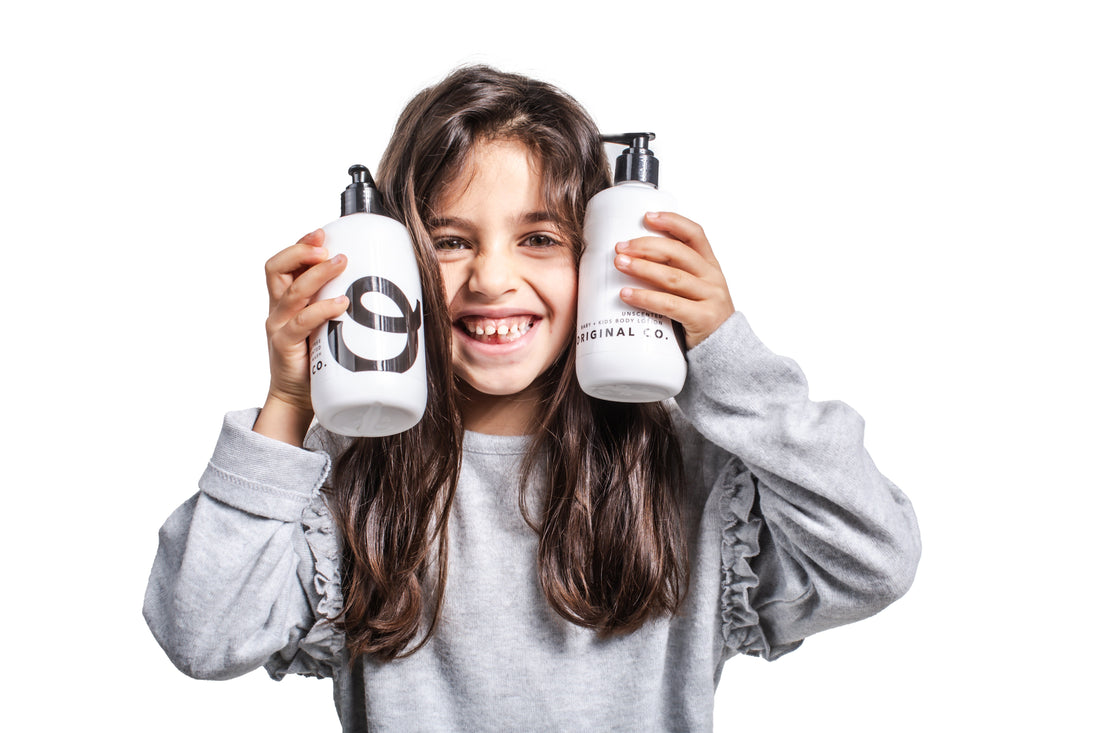 Woman holding The Original Co. baby and kids wash and lotion bottles